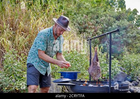 https://l450v.alamy.com/450v/2crytfa/chef-cooking-over-open-flame-at-campsite-along-streambed-2crytfa.jpg