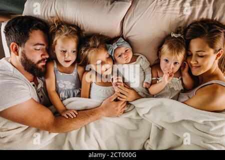 Large family laying in bed with many children and holding hands Stock Photo