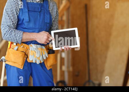 Construction worker at site pointing at blank digital tablet pc with copy space for text Stock Photo