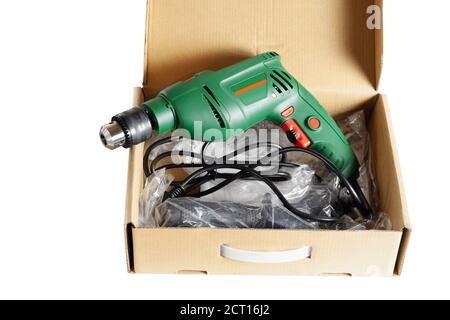 New electric drill in a cardboard box. Close-up. Isolated over white background. Stock Photo
