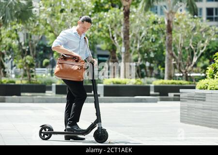 Businessman standing on scooter Stock Photo