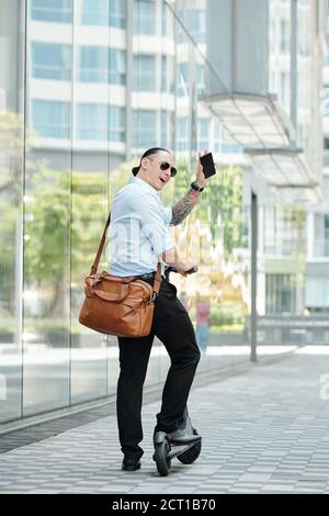 Stylish businessman standing on scooter Stock Photo