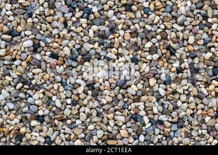 Small cobblestone pebble pieces mixed with asphalt in a paved road close up. Abstract full frame texture background. Stock Photo