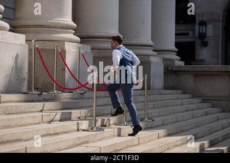 A waiter runs up the steps of Royal Exchange where Fortnum & Mason have set up an outdoor restaurant and bar opposite the Bank of England in the City of London, during the Coronavirus pandemic, on 9th September 2020, in London, England.on 16th September 2020, in London, England. Stock Photo