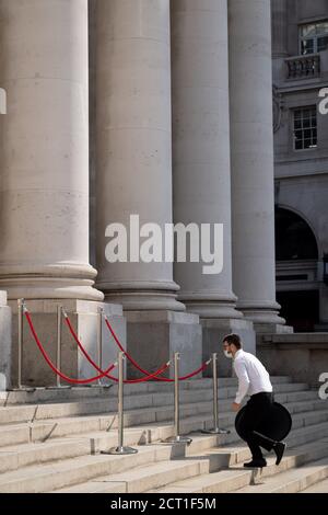 A waiter runs up the steps of Royal Exchange where Fortnum & Mason have set up an outdoor restaurant and bar opposite the Bank of England in the City of London, during the Coronavirus pandemic, on 9th September 2020, in London, England.on 16th September 2020, in London, England. Stock Photo