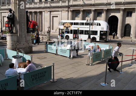 Diners and drinkers sit within street barriers where Fortnum & Mason have set up an outdoor restaurant and bar in front of the Royal Exchange at Bank, in the City of London, during the Coronavirus pandemic, on 9th September 2020, in London, England. Stock Photo