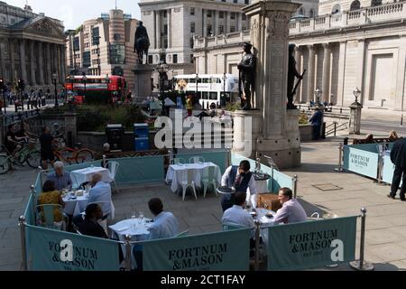 Diners and drinkers sit within street barriers where Fortnum & Mason have set up an outdoor restaurant and bar in front of the Royal Exchange at Bank, in the City of London, during the Coronavirus pandemic, on 9th September 2020, in London, England. Stock Photo