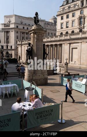 Diners and drinkers sit within street barriers where Fortnum & Mason have set up an outdoor restaurant and bar in front of the Royal Exchange at Bank, in the City of London, during the Coronavirus pandemic, on 9th September 2020, in London, England. Stock Photo