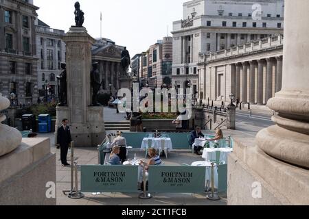 Diners and drinkers sit within street barriers where Fortnum & Mason have set up an outdoor restaurant and bar in front of the Royal Exchange at Bank, in the City of London, during the Coronavirus pandemic, on 9th September 2020, in London, England. Stock Photo