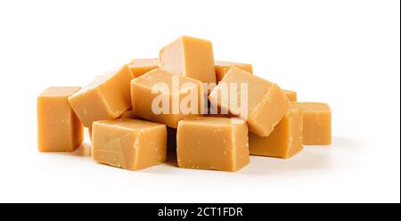Heap of caramel vanilla fudge isolated on white background. Fresh tasty candies made of milk and sugar. Square pieces of delicious chewy soft sweets. Stock Photo