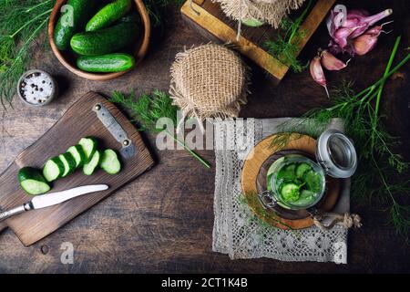 Preparation for pickling cucumbers. Homemade cucumbers cutted into slices with dill and garlic on rustic wooden background. Harvesting vegetables for Stock Photo