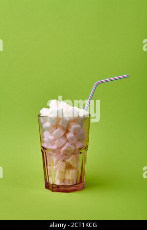 Glass with drinking straw is full of sugar cubes. Stock Photo