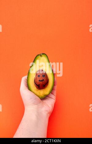 Woman's hand holding avocado. Stock Photo