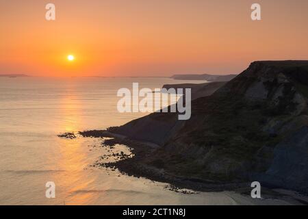 Worth Matravers, Dorset, UK.  20th September 2020.  UK Weather.  The sky glows orange at sunset above Chapmans Pool and the cliffs of Houns Tout on the Jurassic Coast near Worth Matravers in Dorset during the last few days of the autumn heatwave before the weather is forecast to cool down.  Picture Credit: Graham Hunt/Ģ����ý Live News Stock Photo