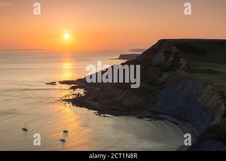Worth Matravers, Dorset, UK.  20th September 2020.  UK Weather.  The sky glows orange at sunset above Chapmans Pool and the cliffs of Houns Tout on the Jurassic Coast near Worth Matravers in Dorset during the last few days of the autumn heatwave before the weather is forecast to cool down.  Picture Credit: Graham Hunt/Ģ����ý Live News Stock Photo