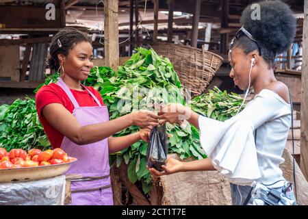 african woman selling in a local african market to a customer Stock Photo