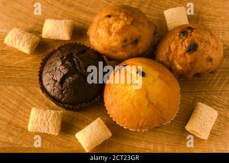 Cupcakes and airy crispy corn pads scattered on a wooden board Stock Photo
