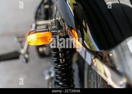 Rear lens of left turn light on vintage motorcycle shines bright as a warning to other drivers. Stock Photo