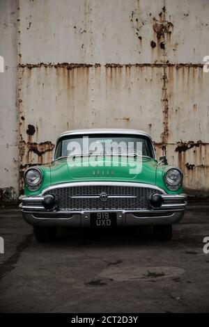 A Green 1955 Buick Century against a an old hanger Stock Photo