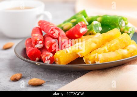 Set of various traditional turkish delight (rahat lokum) in blue ceramic plate with cup of coffee on a gray concrete background. side view, close up, Stock Photo