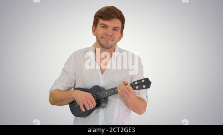 Smiling young man playing ukulele looking into the camera on gra Stock Photo
