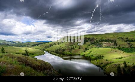 Lightning Strikes from Dark Clouds over Napier Lake in the Grasslands along Highway 5A between Kamloops and Merritt in British Columbia, Canada Stock Photo