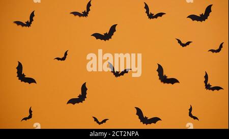 Halloween decoration concept - seamless pattern with black paper bats on orange background, flat lay.Celebration of the dead. Stock Photo