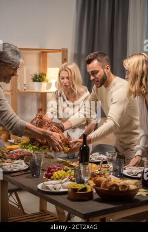 Young and matue men holding tray with homemade roasted turkey over table Stock Photo