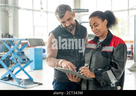 Young female worker of car maintenance service pointing at document Stock Photo