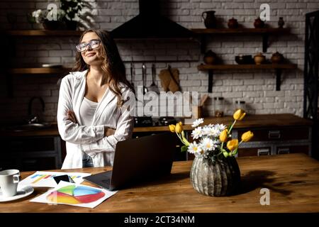 Happy business lady working from home . Beautiful lady working with documents at the kitchen  Stock Photo