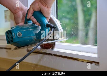 Carpenter using hands cutting wood with electric saw Stock Photo