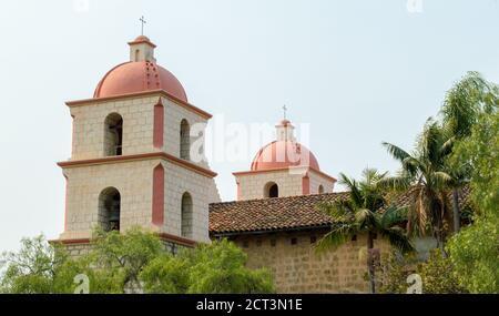 Neoclassical bell towers at the historic Santa Barbara mission amid lush trees under hazy sunshine with copy space Stock Photo