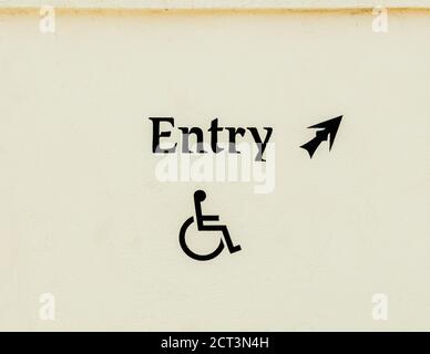 a weathered sign pointing to a handicapped entrance at a beach pavilion Stock Photo