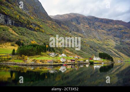 Small village on the waterfront and mountains in the autumn season that reflect the water. Watch from a boat trip to see the beauty of Sognefjord Crui Stock Photo