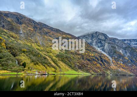 Small village on the waterfront and mountains in the autumn season that reflect the water. Watch from a boat trip to see the beauty of Sognefjord Crui Stock Photo