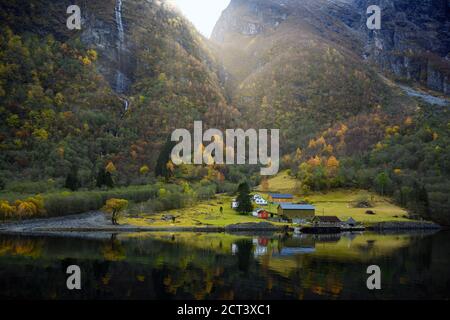 Small village on the waterfront and mountains in the autumn season that reflect the water. Watch from a boat trip to see the beauty of Sognefjord Crui Stock Photo