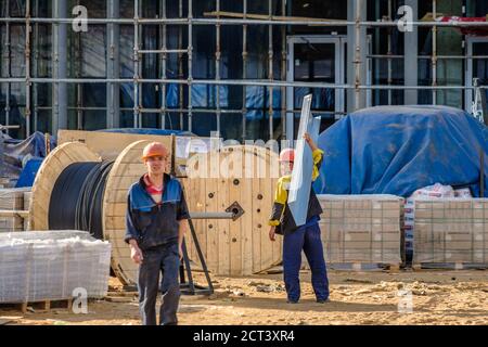 Moscow. Russia. 06 September 2020 Construction workers in uniforms and safety helmets at the construction site manually transfer construction Stock Photo