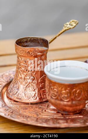 Traditional black bosnian coffee in beautiful copper cezve at wooden table Stock Photo