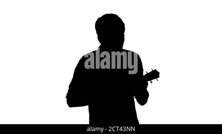 Silhouette Young man playing ukulele and signing while walking. Stock Photo