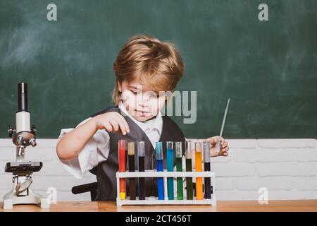 Science. Preschooler. Little kid scientist earning chemistry in school lab. Child in the class room with blackboard on background. Stock Photo