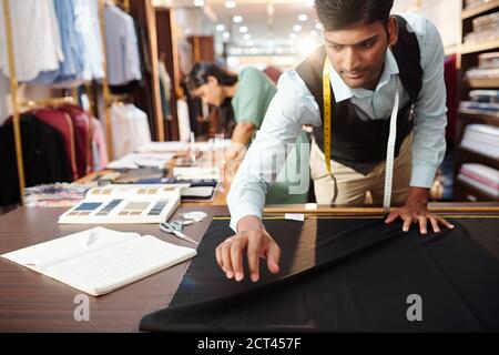 Tailor laying out black fabric Stock Photo
