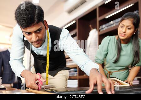 Tailor cutting out suit details Stock Photo