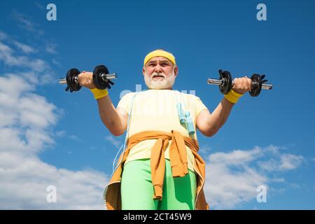 Health club or rehabilitation center for elderly aged pensioner. Senior sport man lifting dumbbells in sport center. Stock Photo