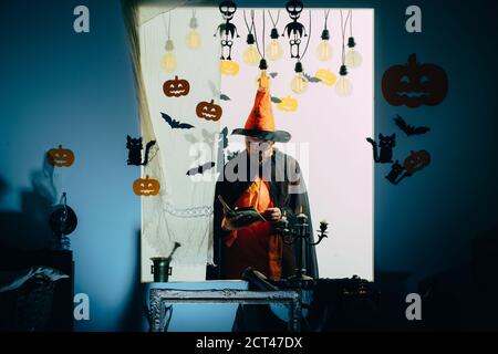 Halloween man with smile on dark background. Holiday celebration symbols on brick wall. Halloween, holidays celebration. Stock Photo