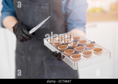 Confectioner girl holds form for candy made of Belgian chocolate Stock Photo