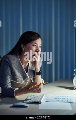 Yawning woman working in office Stock Photo