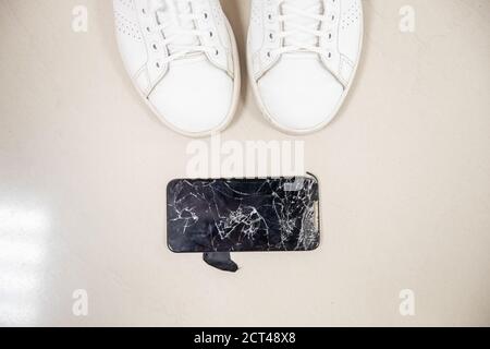 Broken glass of screen phone lies feet of girl, fell drop from great height Stock Photo