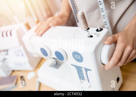 Hands of seamstress work sewing machine for production of dresses in workshop Stock Photo
