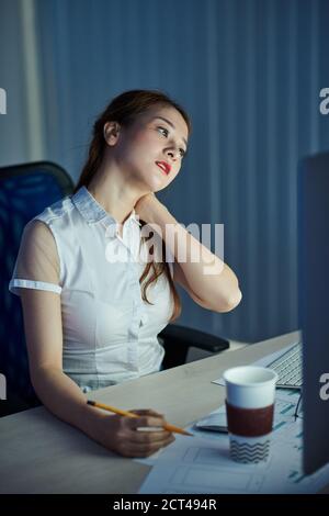 Office worker rubbing her neck Stock Photo - Alamy