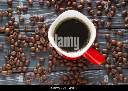 Red cup of coffee between beans on a wooden table Stock Photo